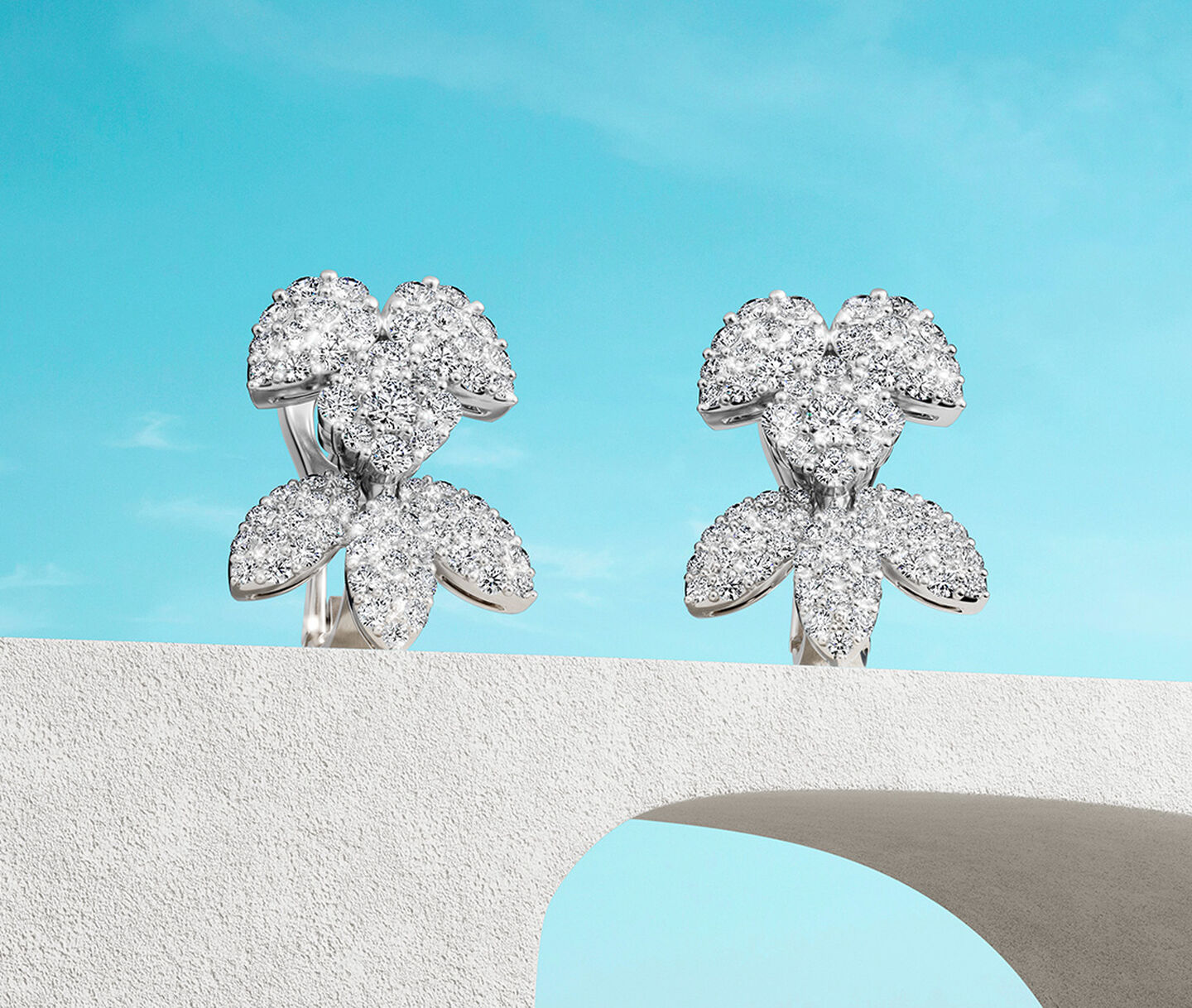 Birks Snowflake snow angel diamond earrings on a sky background.